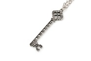 Uroczy, bogato inkrustowany klucz w kolorze srebra, wykonany ze stopu metali nieszlachetnych, zawieszony na długim łańcuszku